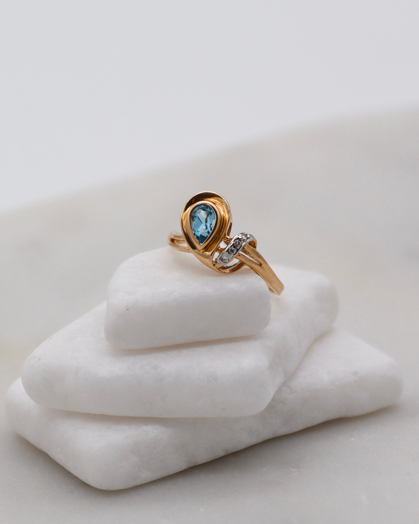 Eleganter Vintage-Ring Aretha mit birnenförmigem blauem Topas (0.20ct) und vier funkelnden Diamanten (0.03ct) in 585 Gelbgold. Erhältlich in München & Augsburg.