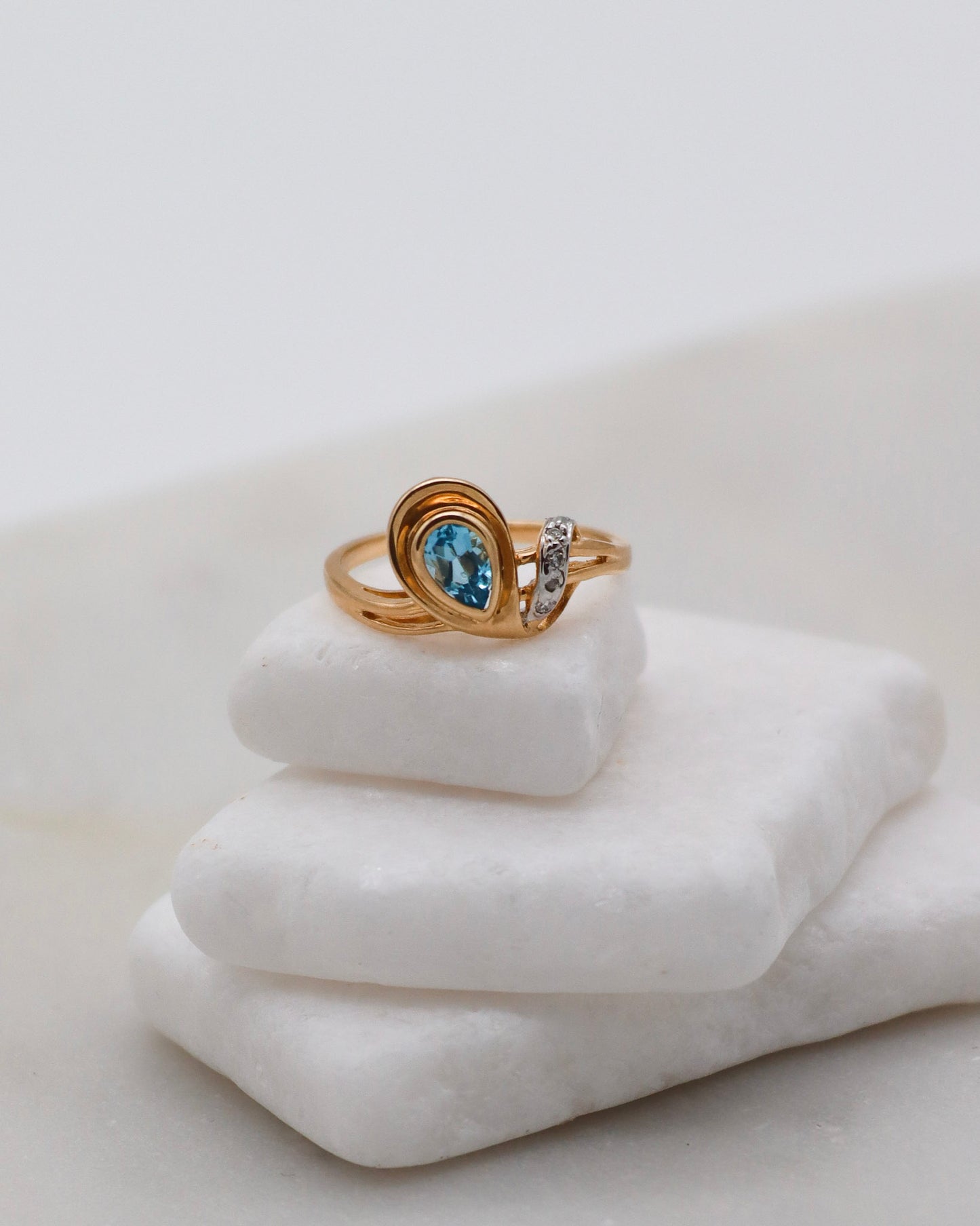 Eleganter Vintage-Ring Aretha mit birnenförmigem blauem Topas (0.20ct) und vier funkelnden Diamanten (0.03ct) in 585 Gelbgold. Erhältlich in München & Augsburg.